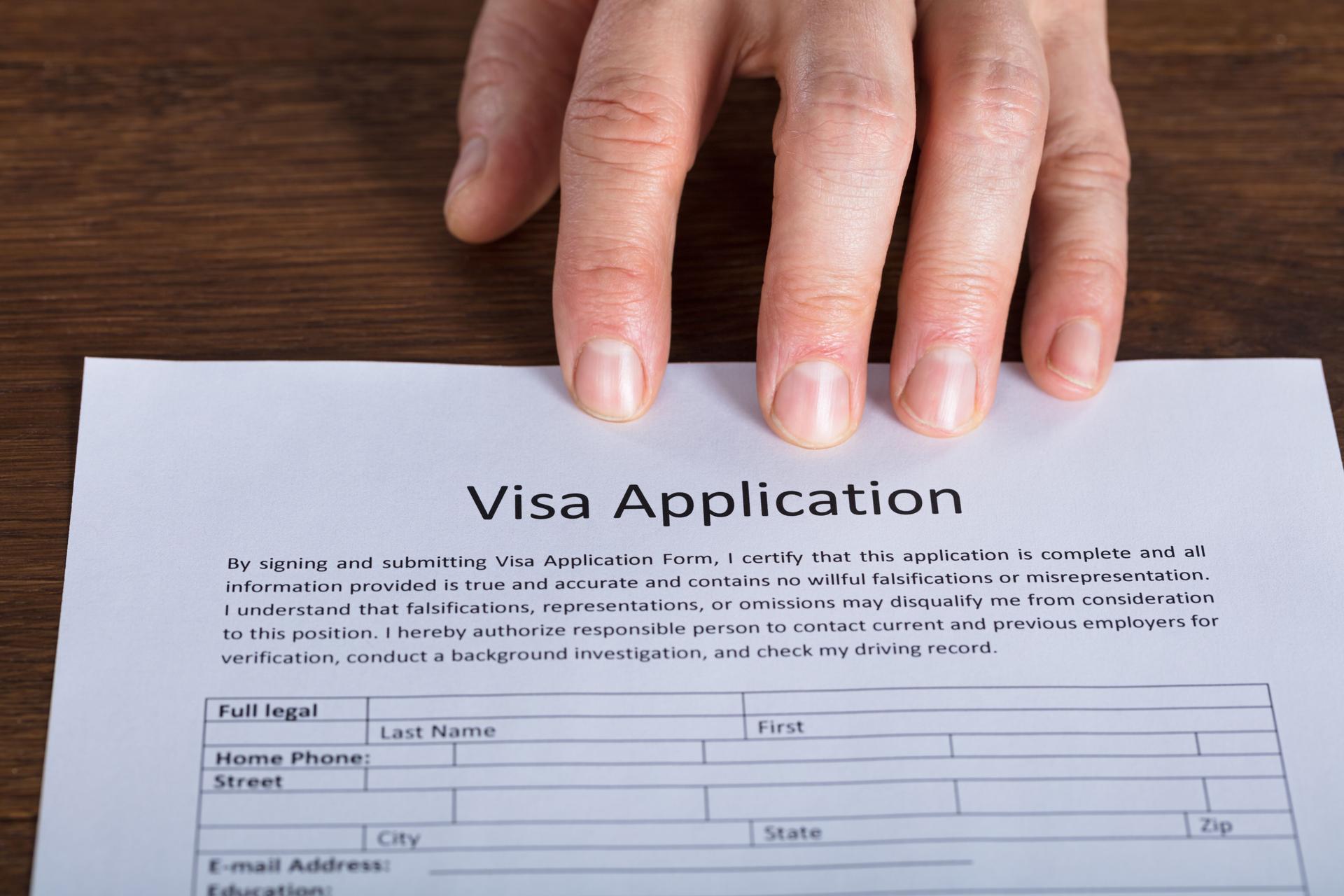 Person Hand On Visa Application Form